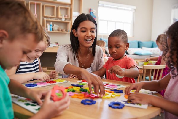 Teacher with preschoolers at shape table